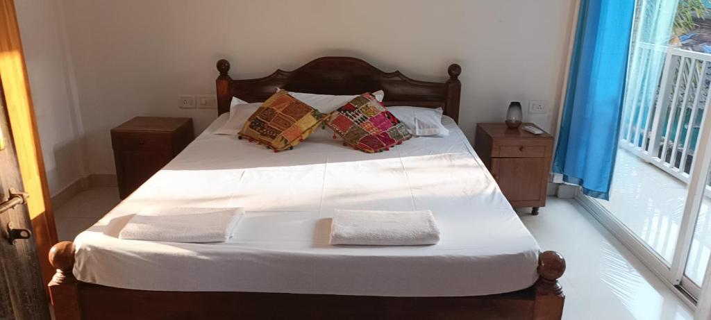 a bedroom with a bed with white sheets and pillows at Casa Branca in Siolim