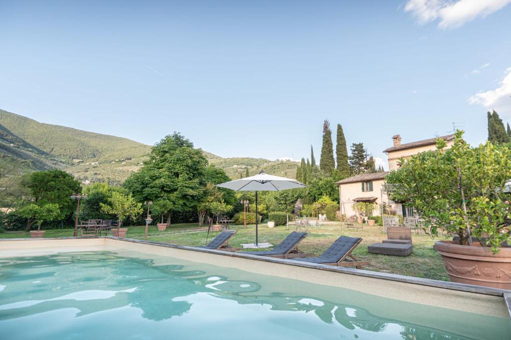 a swimming pool with two chairs and an umbrella at Il Borgo delle Pampare in Campello sul Clitunno