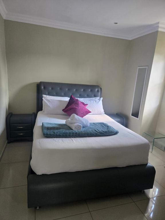 a bedroom with a large bed with purple and pink pillows at Aquasaints Sandton Logde in Johannesburg