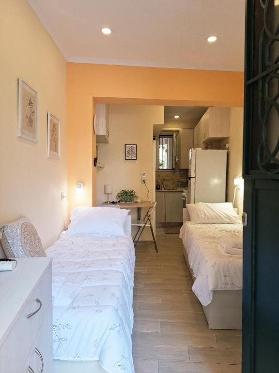 a room with two beds and a kitchen with a refrigerator at il tesorino di Corfu in Corfu