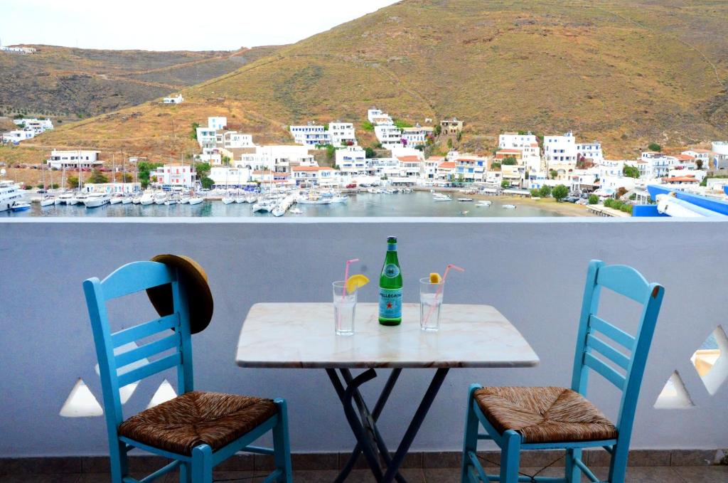 a table with two chairs and a bottle and two glasses at Litsas Studios Kythnos in Kithnos