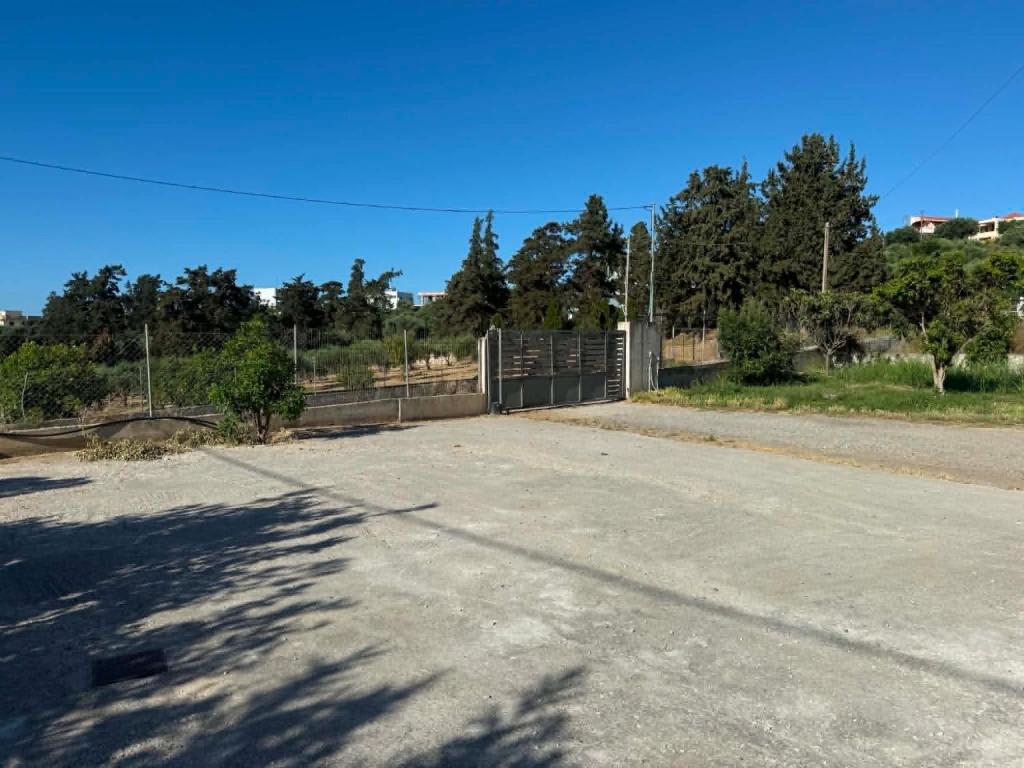 an empty parking lot with a gate and trees at PETROKALIVa in Galatás
