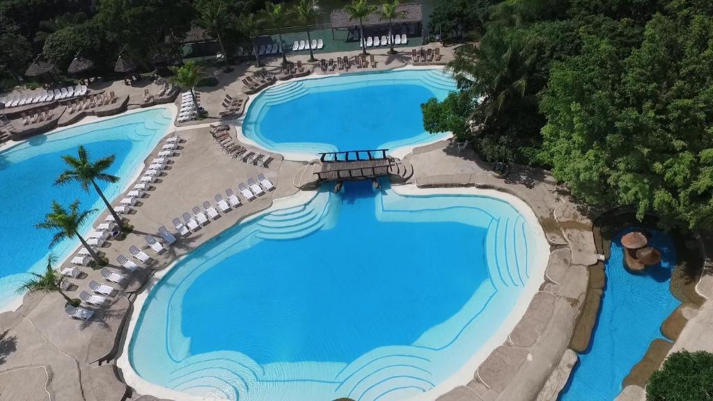 an overhead view of two swimming pools with loungers around them at Güembé Hotel Lodge & Resort in Santa Cruz de la Sierra