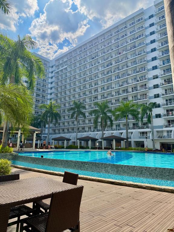 a large hotel with a swimming pool in front of a building at Shell Residences MOA by Jersey in Manila
