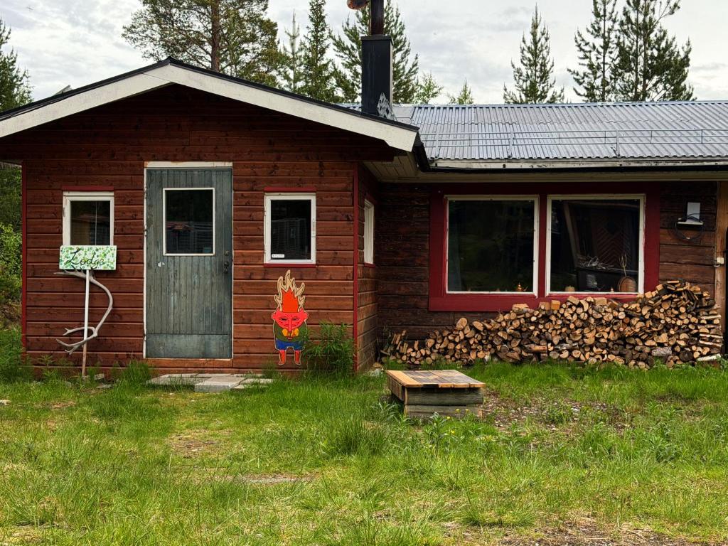 a small house with a door and a pile of fire wood at Holy Motors camp in Kvikkjokks Kapell