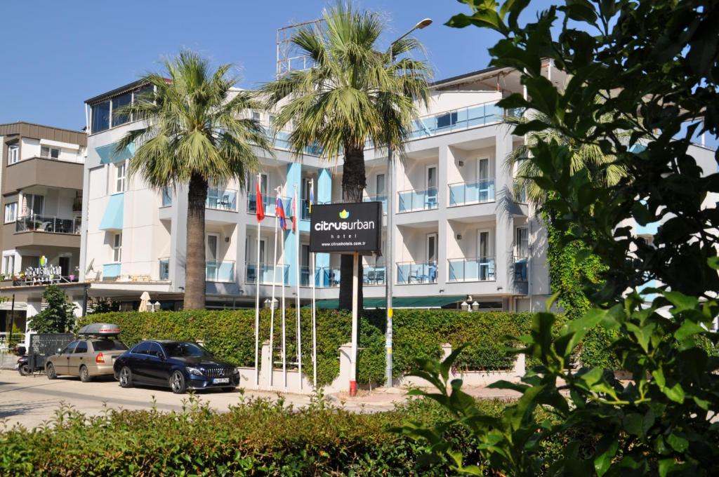 a sign in front of a building with palm trees at Citrus Urban Hotel in Antalya