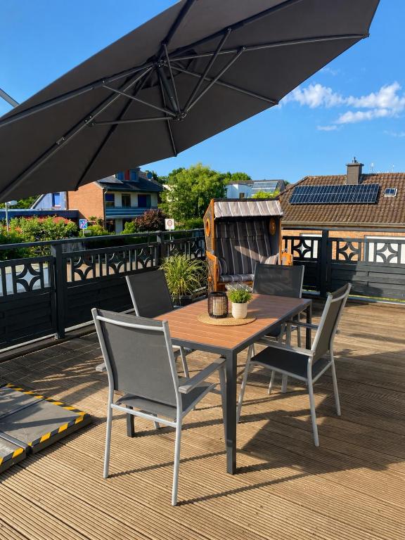 a wooden table with chairs and an umbrella on a deck at FeWo Auszeit eigene große Terrasse mit Strandkorb und Grill in Wesel