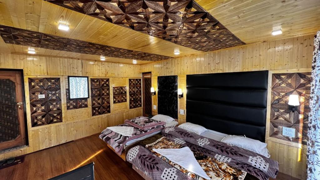 a room with four beds in it with wooden walls at Star Palace in Pahalgām