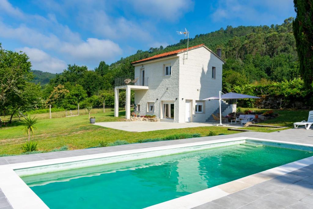 a villa with a swimming pool in front of a house at o fogar do cipres in Rivela