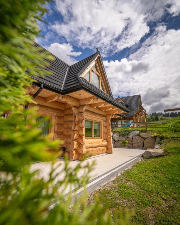 a log home with a black roof at Osada Małe Ciche DOMEK z Bali in Małe Ciche