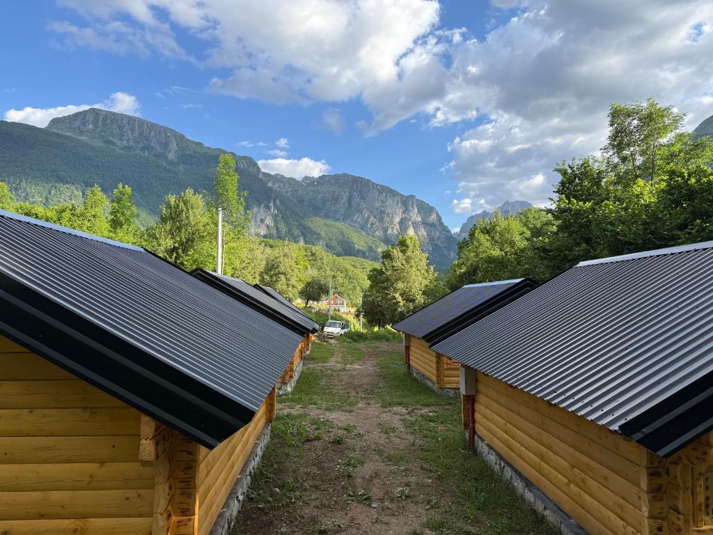 a row of wooden buildings with mountains in the background at Bungalow-Guest House Alpina in Vusanje