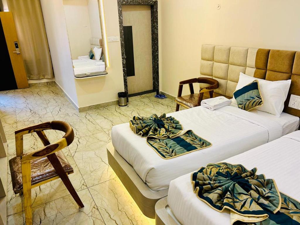 a hotel room with two beds and a mirror at The Hotel Emerald in Koraput