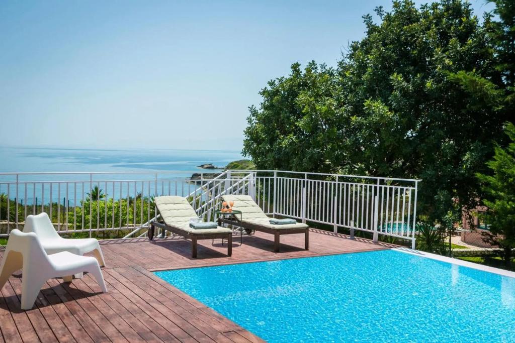 a house with a swimming pool and two chairs at Villas LaVista in Skala