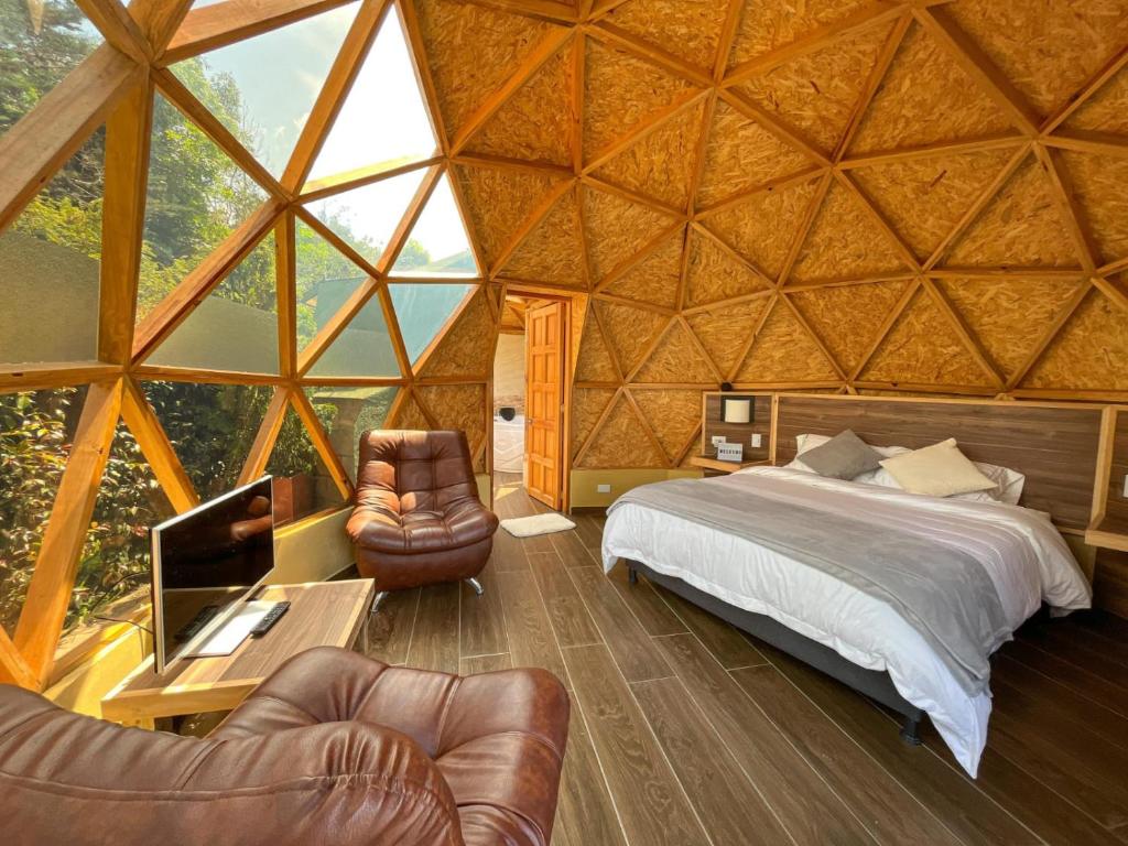 a bedroom in a yurt with a bed and chairs at Glamping Green Garden Suite in Villa de Leyva