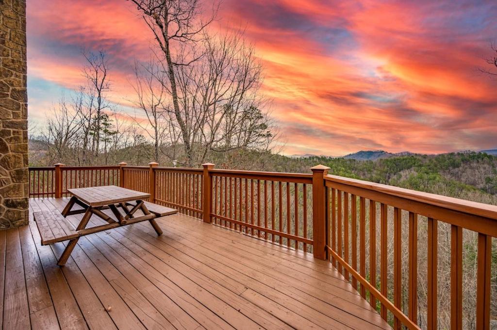 a wooden deck with a picnic table and a sunset at Breathtaking Views No-Stair Entry, Hot Tub, Pool Table & Seasonal Pool Access in Sevierville