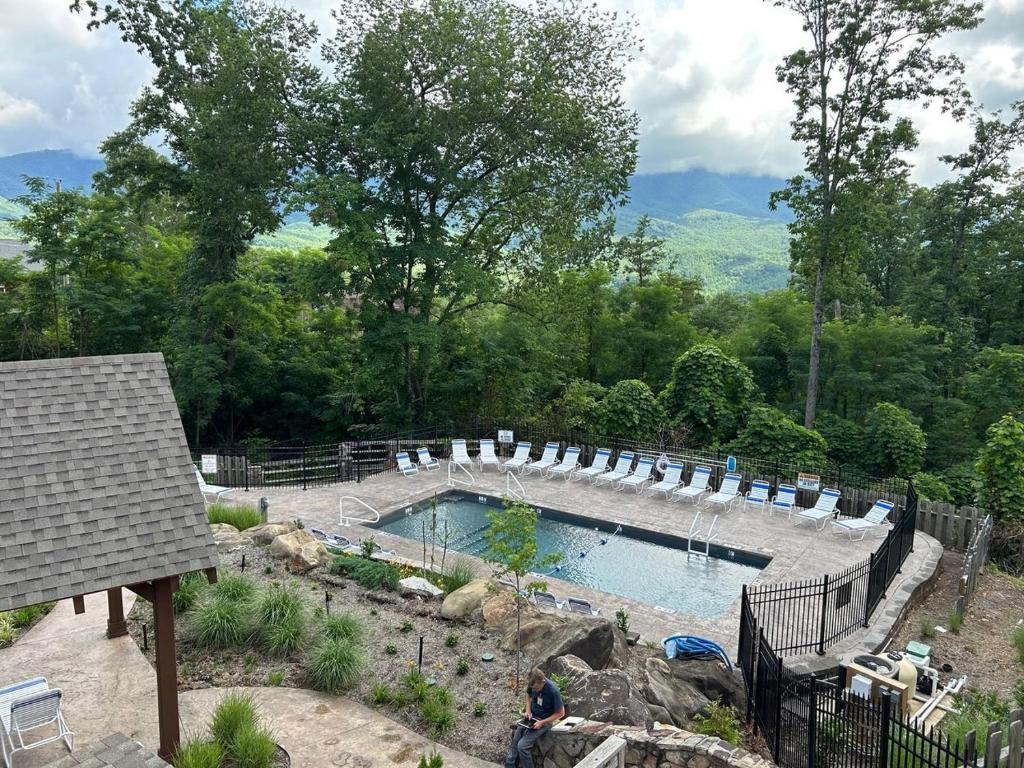 a large swimming pool with chairs in a yard at Happy Trails Stunning Smoky Mtn Views Hot Tub Game Room Resort Pools in Gatlinburg