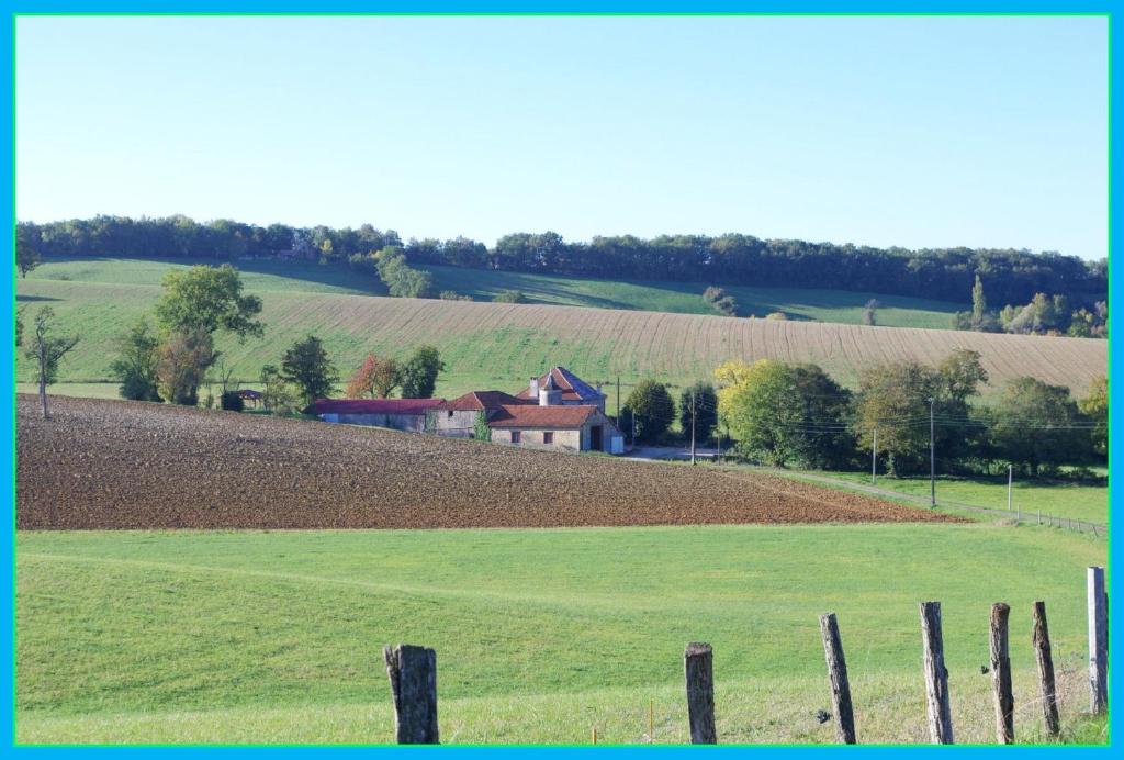 una granja con un campo y una casa en una colina en la prade basse en Saint-Antonin