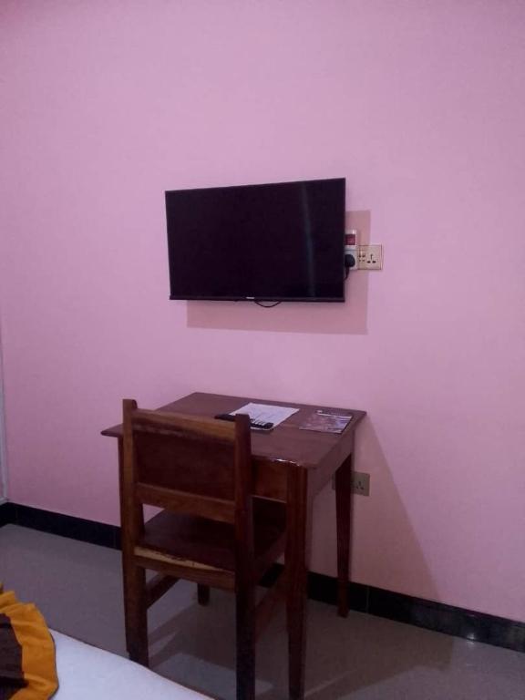 a small table with a chair and a television on a wall at Katavi Empire Hotel in Mpanda