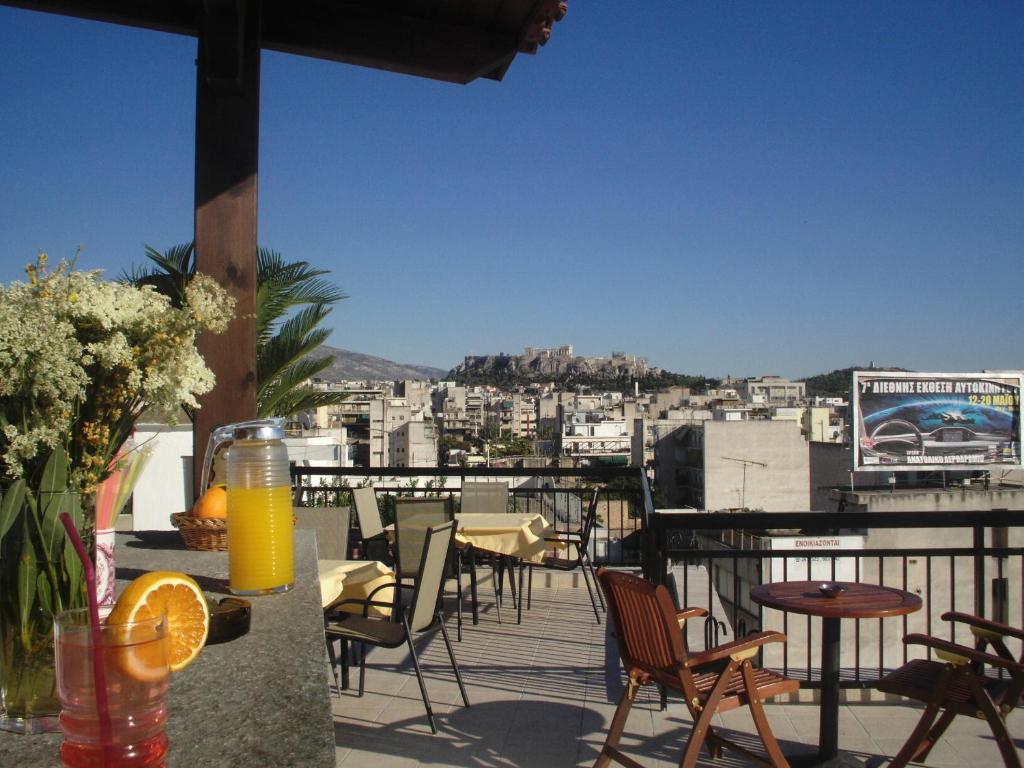 a balcony with tables and chairs and a view of a city at Apollo Hotel in Athens