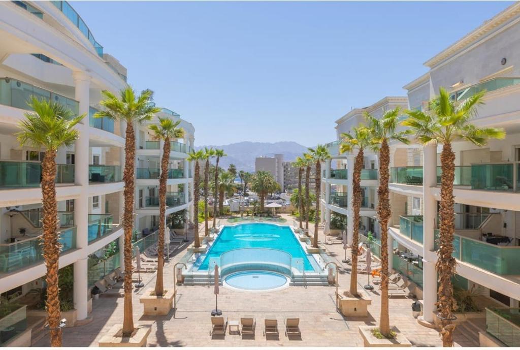 an apartment complex with a swimming pool and palm trees at סוויטת לה פלמורה in Eilat