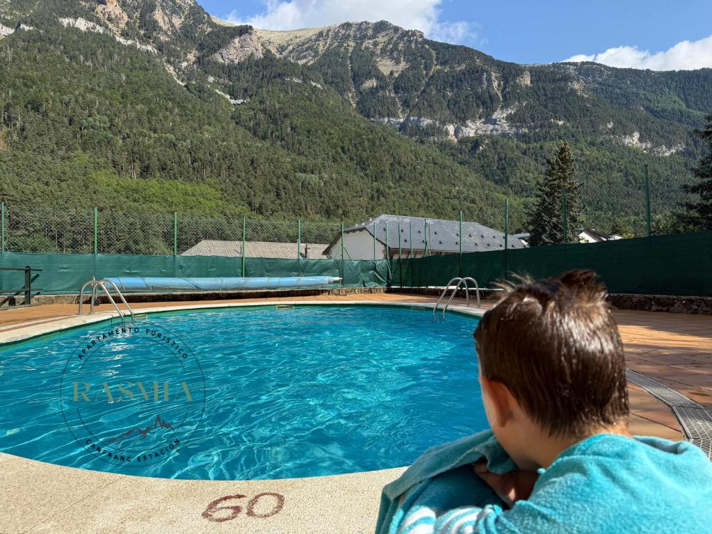 a child is sitting next to a swimming pool at Rasmia Canfranc Estación in Canfranc-Estación
