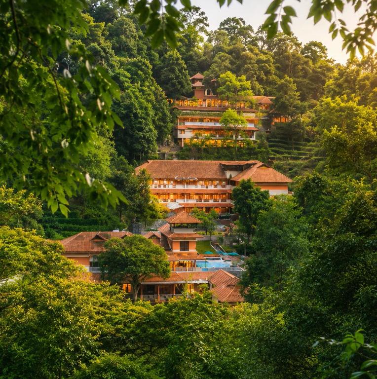 a group of buildings on a hill with trees at Upavan Resort in Vythiri