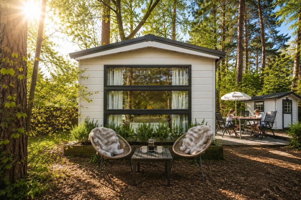 a tiny house in the woods with two chairs and a table at Sfeervol boshuisje op de Veluwe Vossenberg in Nunspeet