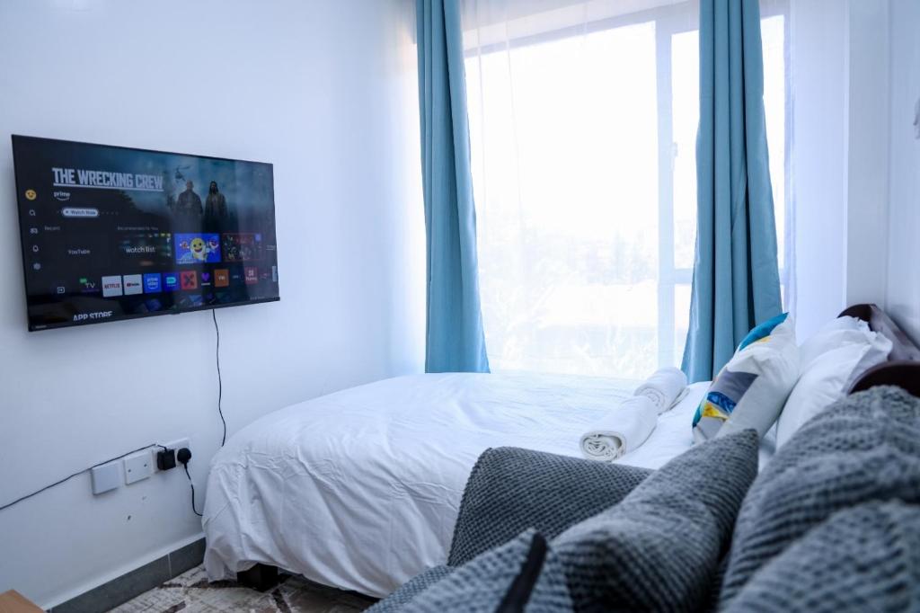 a bedroom with a bed and a tv on the wall at Onkundis Luxury Homes in Kiambu