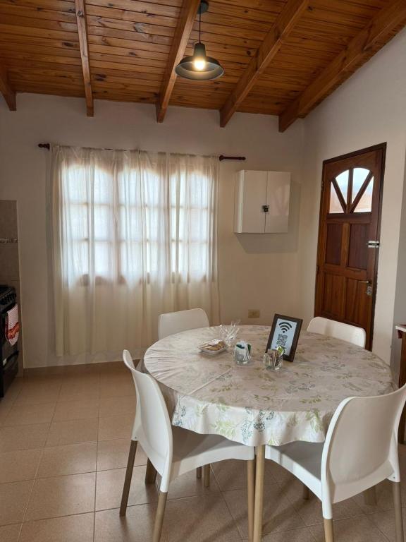 a dining room with a table and white chairs at Alvear Departamento B in Venado Tuerto