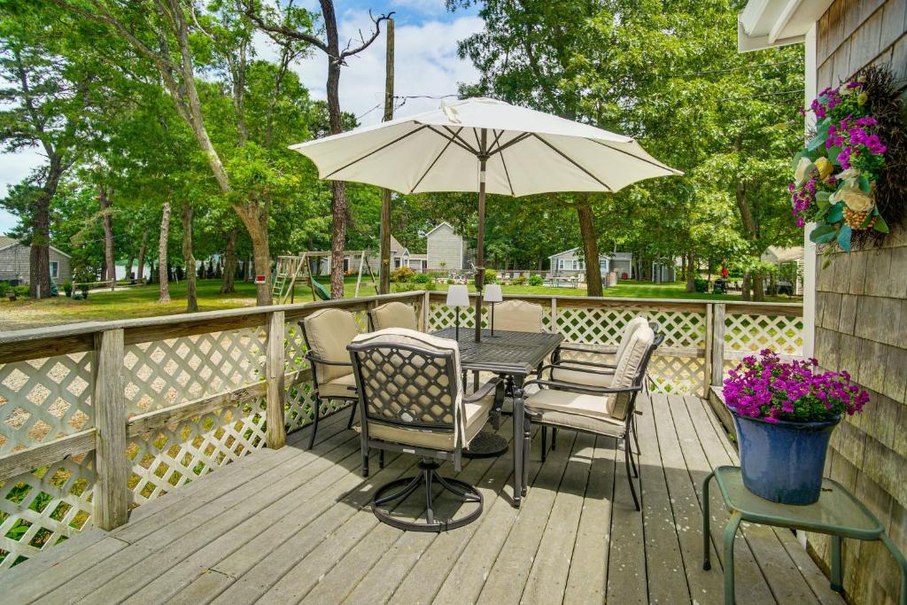 a table and chairs with an umbrella on a deck at Charming Cape Cod Water-View Cottage in Mashpee
