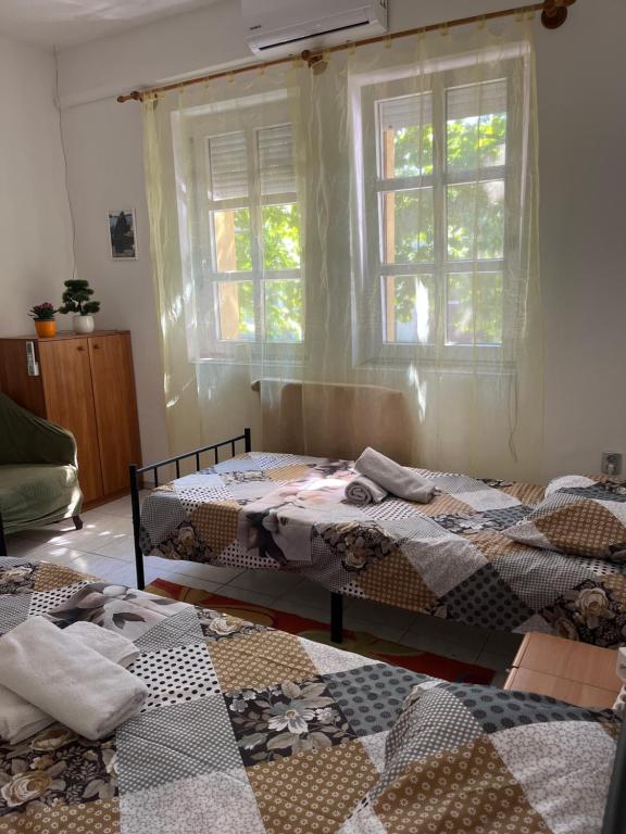 a room with three beds and a window at Mazsola apartman in Hódmezővásárhely
