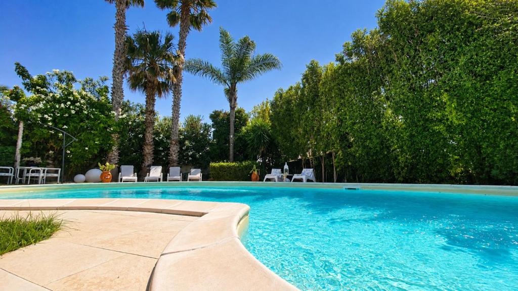 a swimming pool with palm trees and chairs at The Queens House in Agrigento
