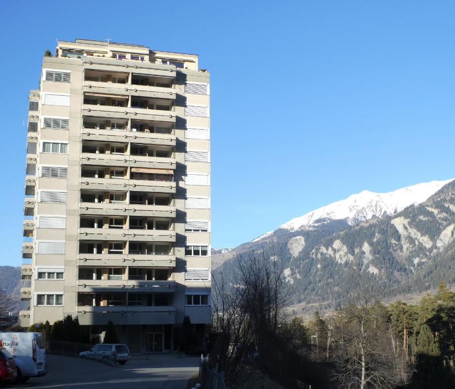 ein hohes weißes Gebäude mit Bergen im Hintergrund in der Unterkunft Viamalablick in Thusis