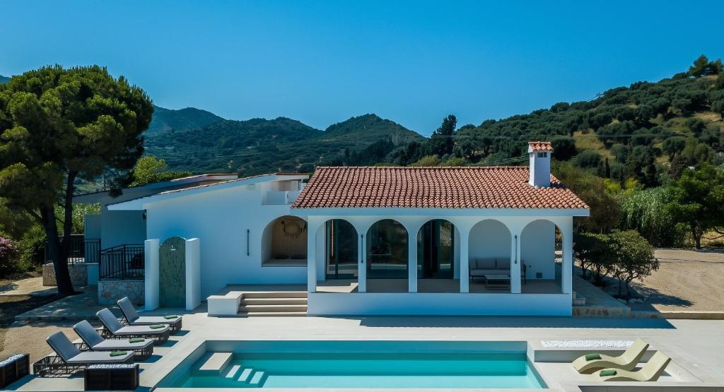 a villa with a swimming pool and lounge chairs at Xenia Sea view Villa in Argassi