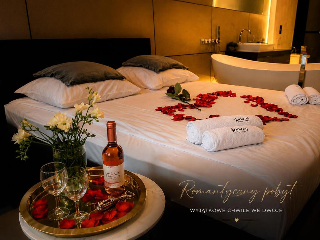 a bed with a bottle of wine and flowers on it at Apartament z jacuzzi City Life Centrum in Bielsko-Biała