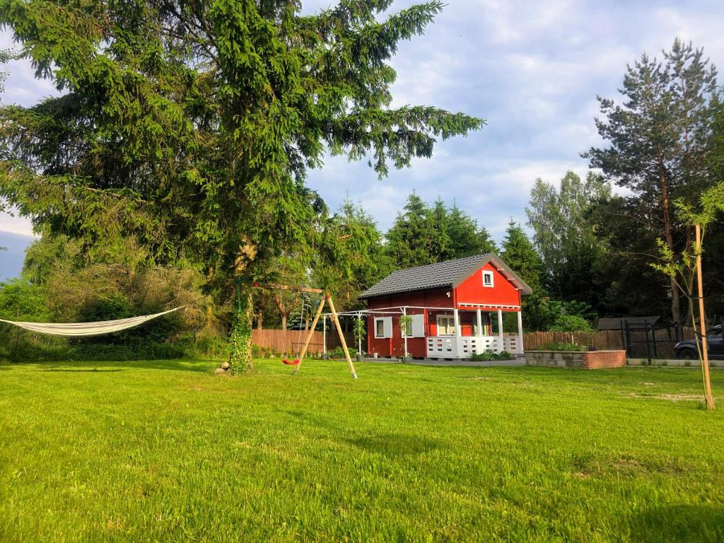 a hammock in a yard with a red house at Mazury na Miedzy in Orzyny