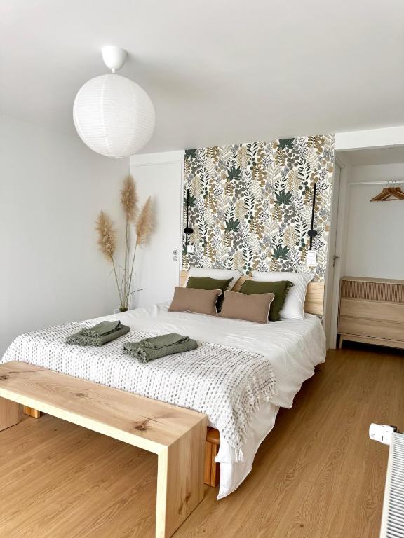 a bedroom with a large white bed with a wooden floor at T2 Cosy in Mende