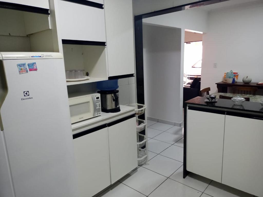 a kitchen with white cabinets and a microwave at recanto sossego in Garanhuns