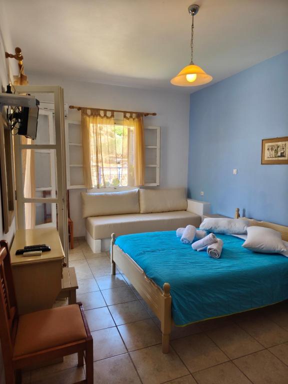 a bedroom with a bed with blue sheets and a couch at Deilino - Olive View Studio in Amorgos