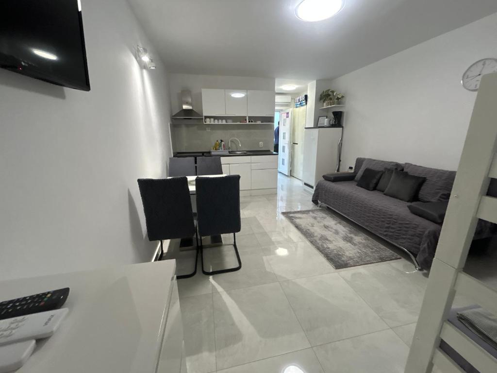 a white living room with a couch and a kitchen at My Miracle Stinica in Stinica