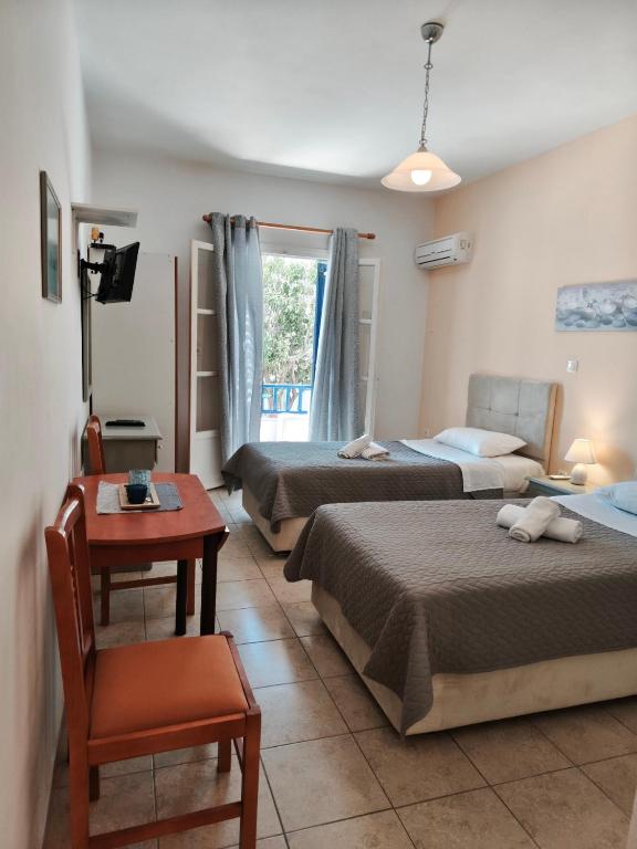 a hotel room with three beds and a table and a chair at Deilino - Side View Studio in Amorgos