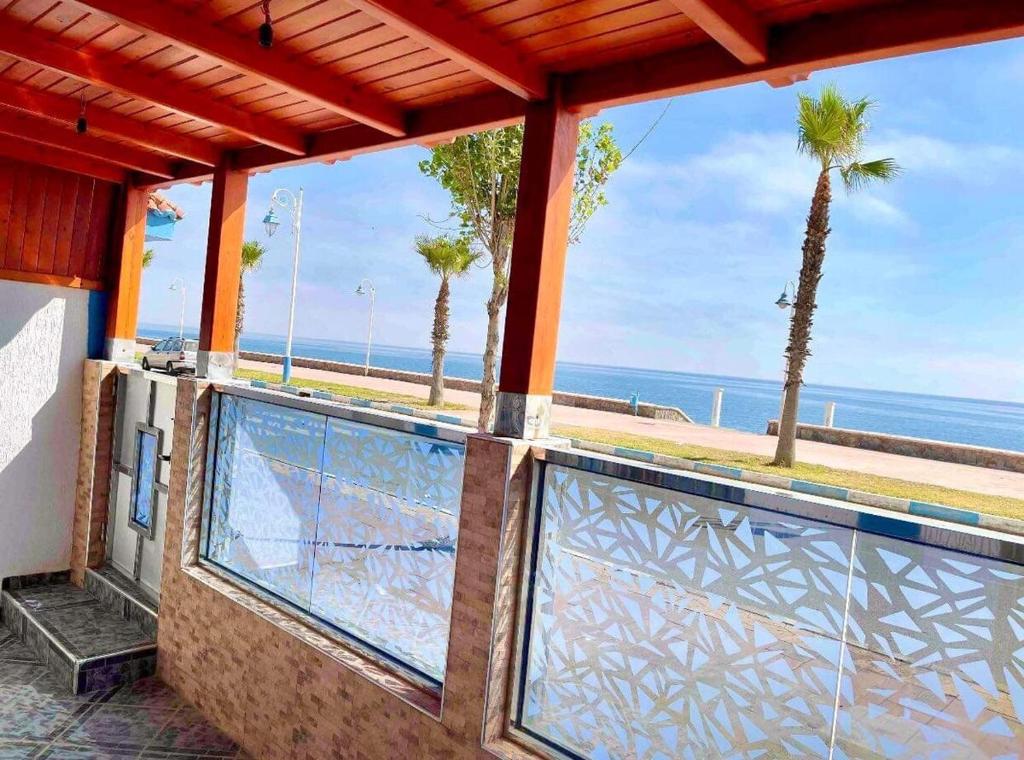 a balcony with a view of the ocean and palm trees at Las Brisas Beachfront Mekad private in Oued Laou