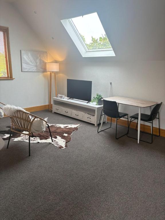 a living room with a tv and a table and chairs at Spacious 1 Bed apartment City centre in Palmerston North