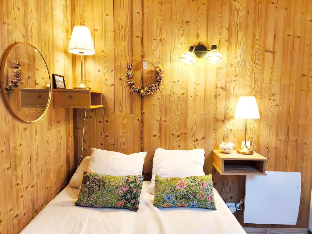 a bedroom with wooden walls and a bed with two pillows at Apparts'Hôtel Aspe in Bedous
