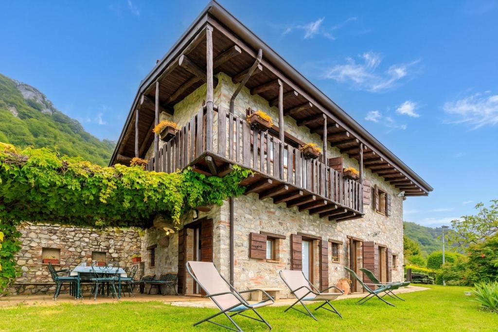 an old stone house with a balcony and chairs at Villa Formaga Stunning View & Garden - Happy Rentals in Gargnano