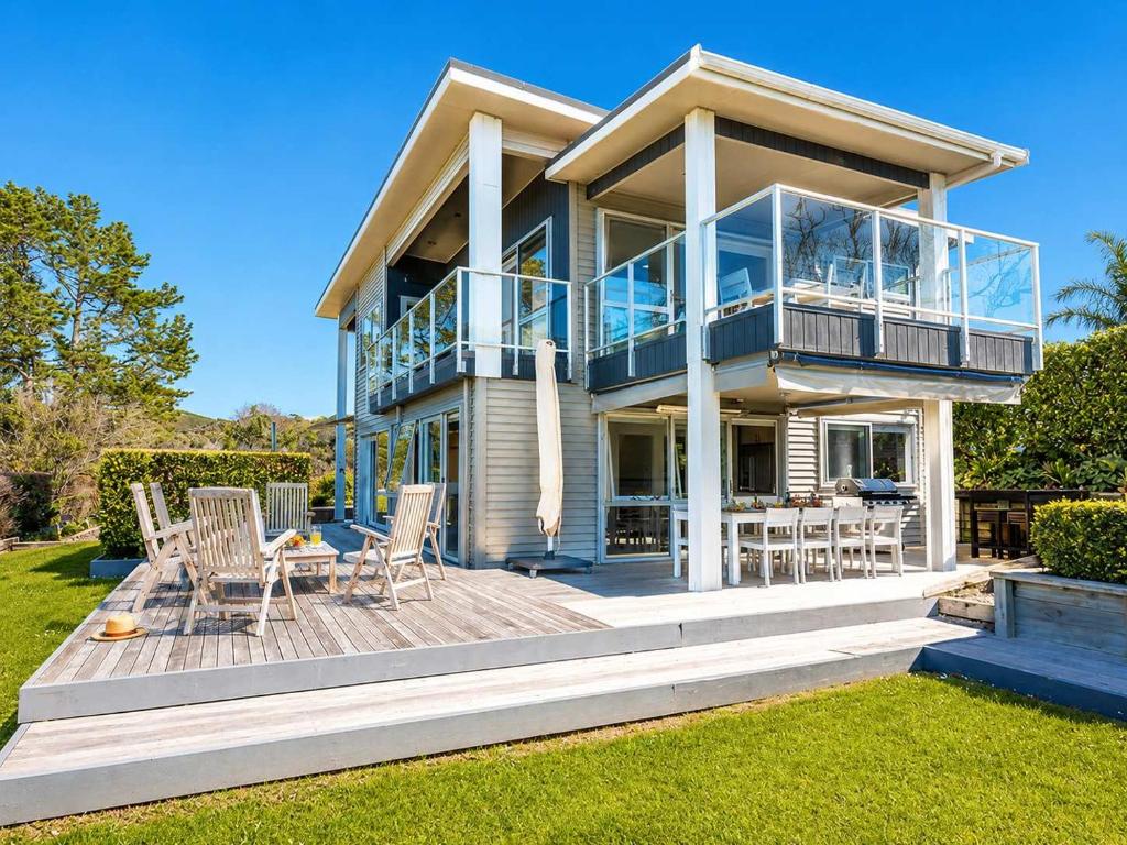 a large house with a deck with chairs on it at Bella Seven- Stay Waiheke in Oneroa