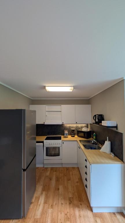 a kitchen with white cabinets and a stainless steel refrigerator at Cozy pet-friendly apartment with parking in Flekkefjord