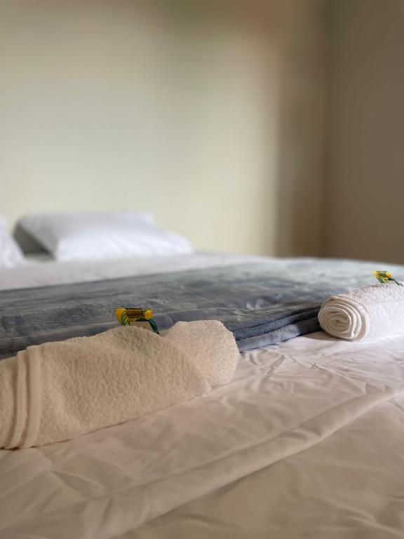 a bed with two towels and two towels on it at Harmony House Hospedagem in Votuporanga
