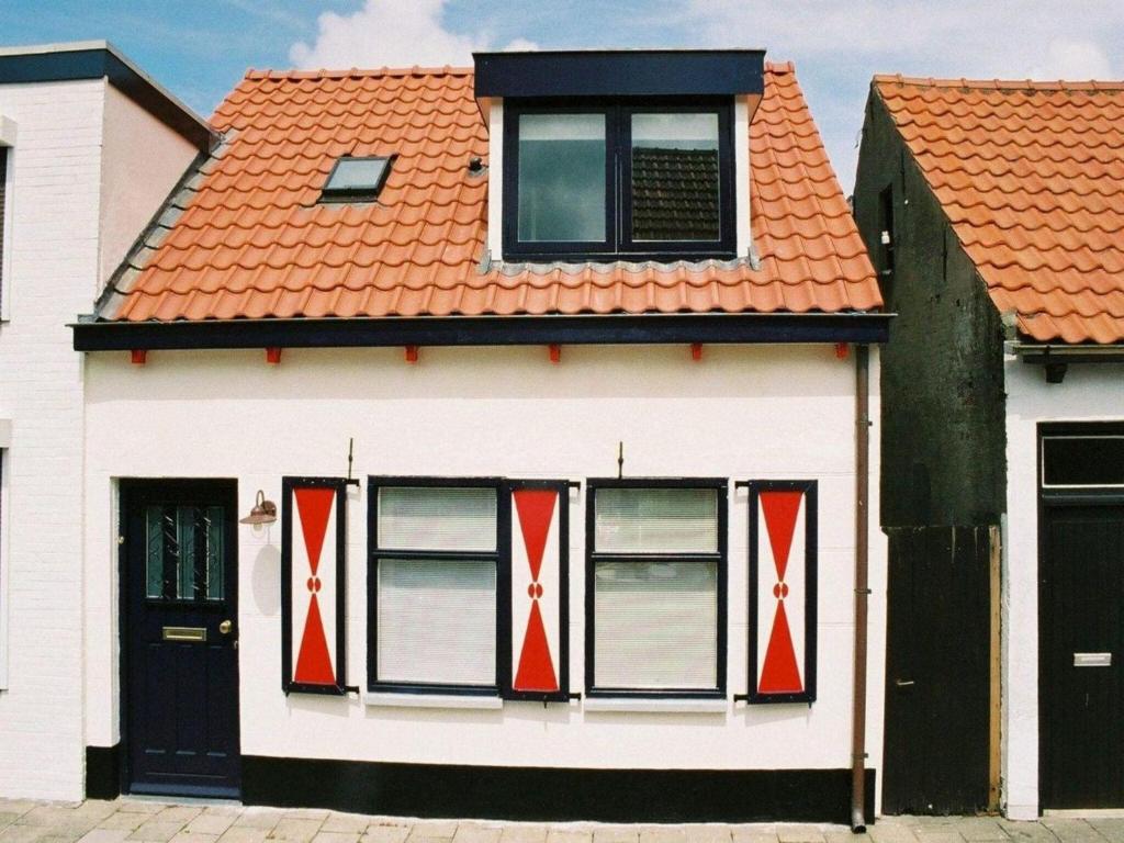 a house with red and white windows and a orange roof at Historic Cottage w Garden in Breskens
