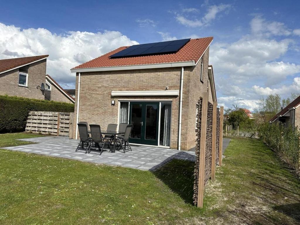 a house with a solar roof and chairs on a patio at Bungalow in Breskens near Beach & Lighthouse in Breskens